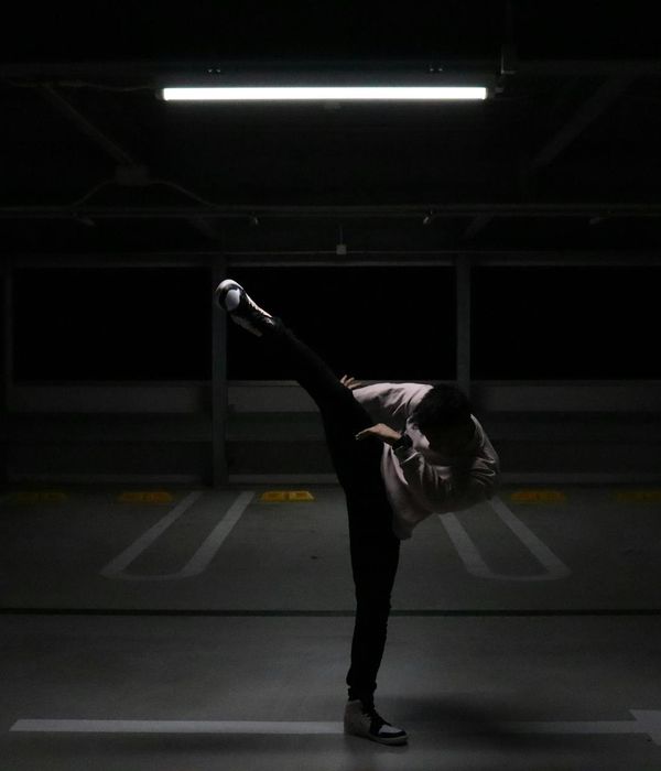 Man performing a controlled strength exercise in a dark room with mint light.